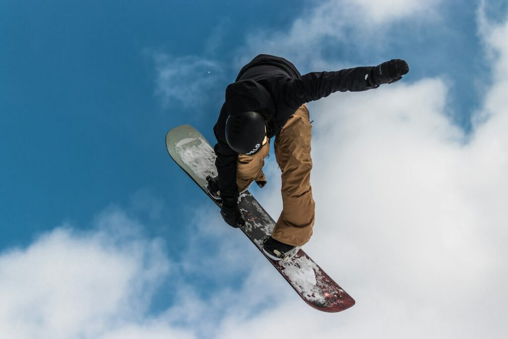 man in black jacket and brown pants riding white and red snowboard